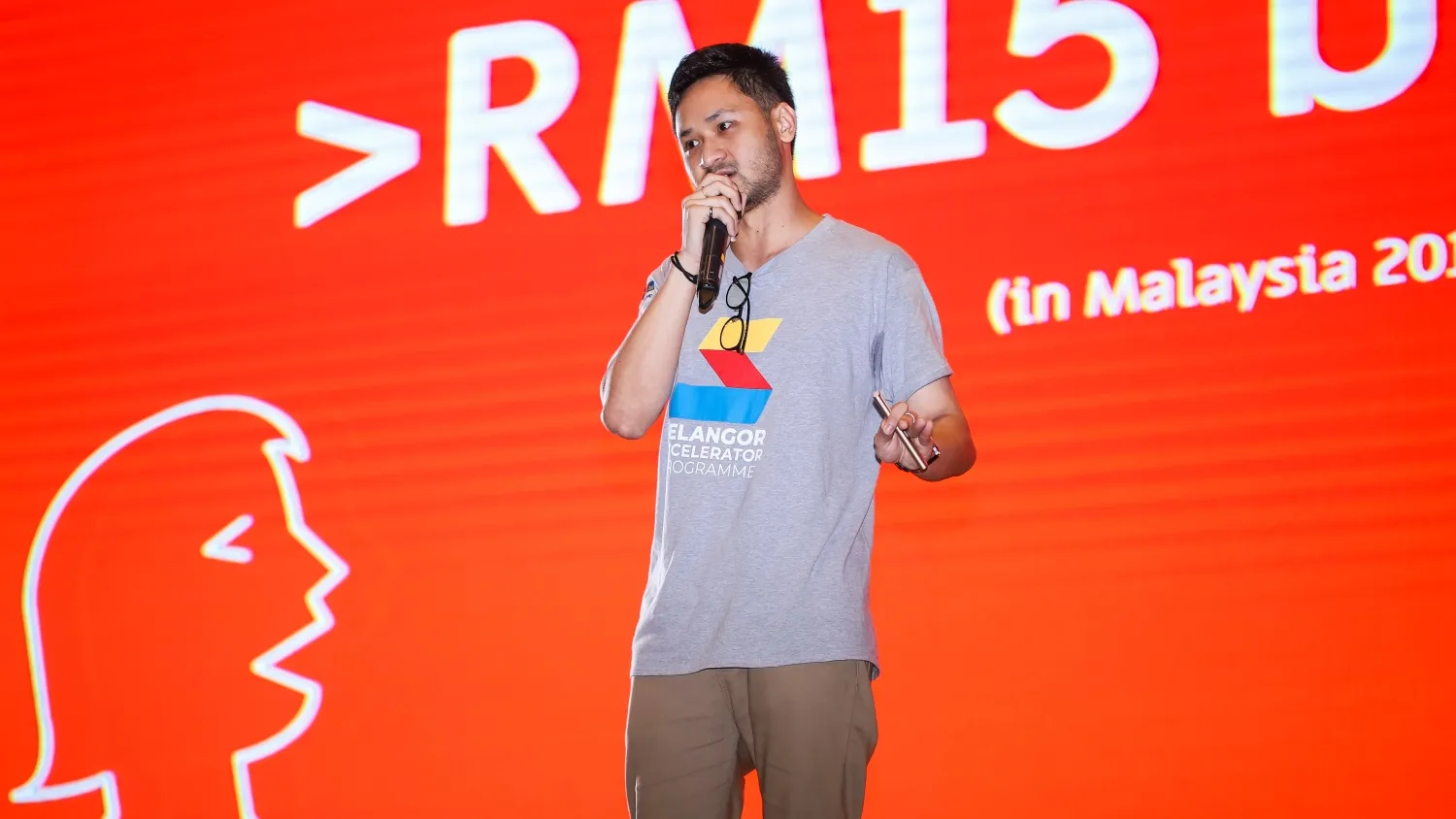 Adam on stage with a microphone, pitching at the Selangor Accelerator Programme